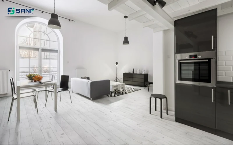 Căn hộ studio lát sàn nhựa giả gỗ trắng với cửa sổ vòm sofa xám và tủ bếp đen