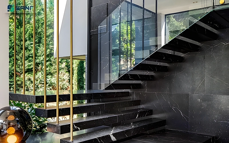 Vách marble đen gân trắng bên cầu thang bậc đá đen nổi với thanh trụ vàng và kính