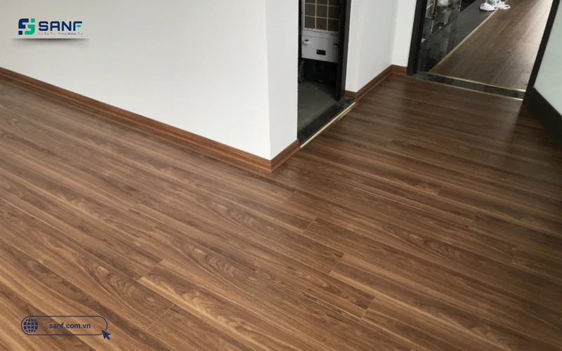 Sàn nhựa giả gỗ tông nâu óc chó lát giật cấp với mối nối so le trong căn phòng tường trắng