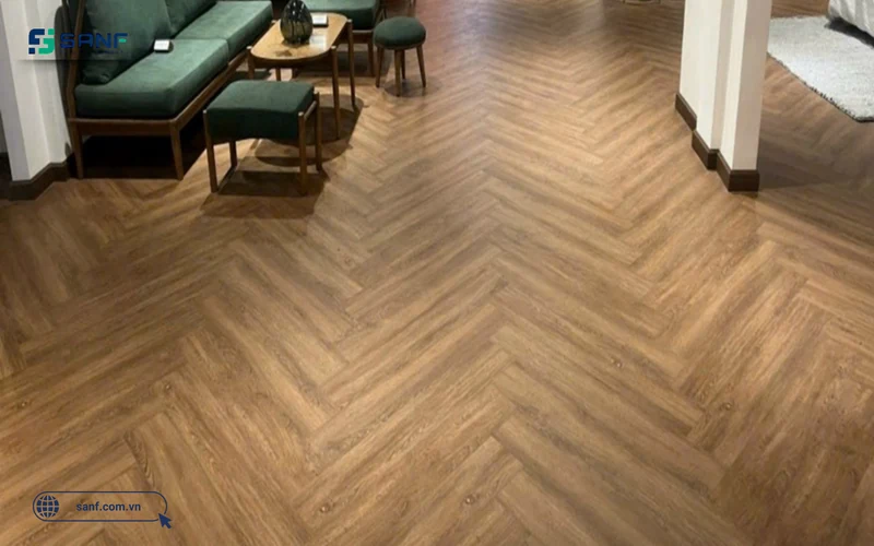 Phòng khách lát sàn nhựa giả gỗ xương cá Herringbone tông nâu vàng kết hợp sofa xanh rêu