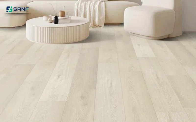 Phòng khách lát sàn nhựa giả gỗ trắng kem mờ với bàn trà tròn và sofa kem