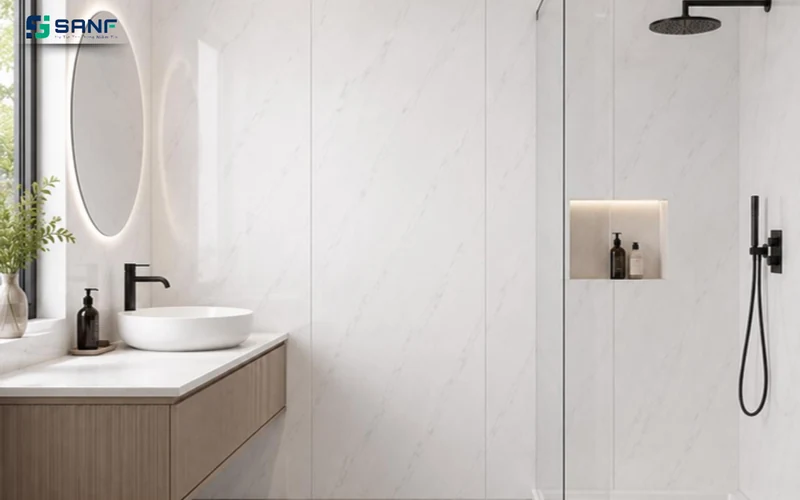 Phòng tắm tường ốp tấm vân đá trắng nhạt chia khe đứng cạnh buồng tắm kính có hốc để đồ