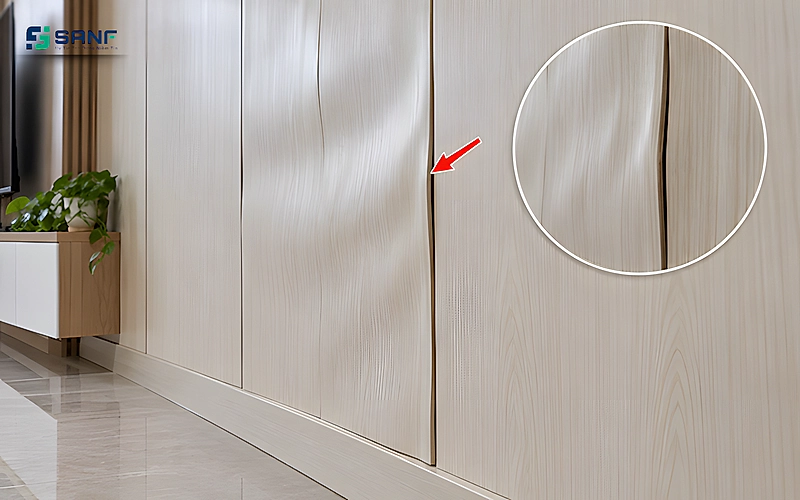 Tấm nano trên tường bị cong vênh gợn sóng cạnh mối nối có mũi tên đỏ và vòng phóng to chi tiết